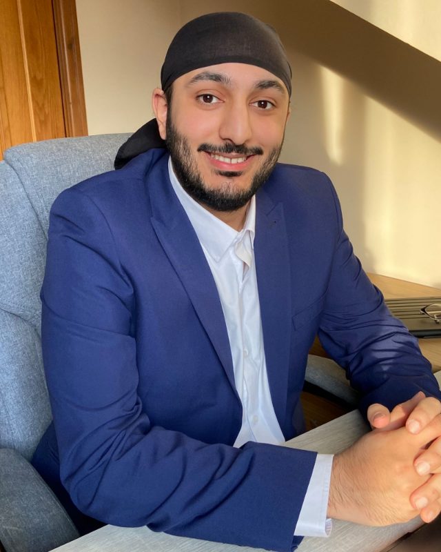 Parambir Randhawa, seated at a desk, smiling